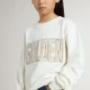 Sudadera blanca para niñas con letras doradas multicolores en la parte delantera